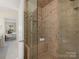 Tiled shower with glass door, a built-in seat, and open doorway to another bathroom space at 232 Perrin Pl, Charlotte, NC 28207