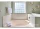 Clean bathroom featuring a soaking tub, tiled walls, and a clear glass block window for natural light at 3009 Thayer Dr, Waxhaw, NC 28173