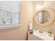 Powder room with cream-colored walls, and a round rattan mirror over a white vanity at 3032 Kilbeggan Dr, Lake Wylie, SC 29710