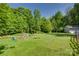 Expansive backyard with lush green grass, a fire pit, and wooded scenery at 3243 Farmcrest Ct, Fort Mill, SC 29708