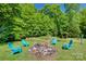 A stone firepit with four turquoise chairs is nestled in a green, wooded backyard at 3243 Farmcrest Ct, Fort Mill, SC 29708