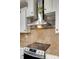 Close up of the cooktop with stainless steel range hood and tile backsplash at 3243 Farmcrest Ct, Fort Mill, SC 29708
