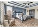 Comfortable main bedroom with a large upholstered chair, hardwood floors, and a tray ceiling at 4071 Thames Cir, Fort Mill, SC 29715