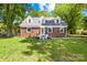 Charming brick home with manicured lawn and inviting front porch with chairs at 6012 Tuckaseegee Rd, Charlotte, NC 28208