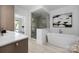 Bright bathroom featuring a glass enclosed shower, modern tub, and marble countertops with wood cabinetry at 614 Queens Rd, Charlotte, NC 28207