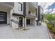 Modern townhouse featuring gray siding, brick accents, and stylish glass garage doors at 614 Queens Rd, Charlotte, NC 28207