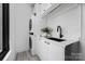 Efficient laundry room features a stacked washer/dryer, black faucet and sink, and sleek white cabinets at 614 Queens Rd, Charlotte, NC 28207