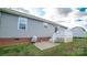 The back exterior showcasing a small backyard patio, gray siding, and a shed at 6300 Bill Sain Rd, Vale, NC 28168