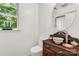 Elegant half bathroom featuring a unique vanity, round mirror, and plenty of natural light at 709 Weldon Ln, Salisbury, NC 28146