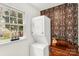 Functional laundry area with a stacked washer and dryer next to a window and dark floral wallpaper at 709 Weldon Ln, Salisbury, NC 28146