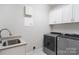 Laundry room with utility sink, cabinets, and modern washer and dryer at 7358 Bay Cove Ct, Denver, NC 28037