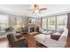 Inviting living room featuring a stone fireplace, hardwood floors, ceiling fan, and abundant natural light at 7405 Albemarle Dr, Denver, NC 28037