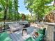Expansive backyard with a deck, outdoor seating, and a playset surrounded by trees at 10024 Whitethorn Dr, Charlotte, NC 28277