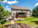 Backyard view of the house with a patio seating area, grill, lawn, and large screened porch at 10944 Persimmon Creek Dr, Mint Hill, NC 28227