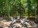 Inviting outdoor fire pit surrounded by Adirondack chairs and lush trees, perfect for gatherings at 10944 Persimmon Creek Dr, Mint Hill, NC 28227
