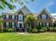 A brick two-story home with a manicured lawn and a meticulously landscaped front yard in a suburban neighborhood at 10944 Persimmon Creek Dr, Mint Hill, NC 28227