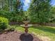 Beautiful backyard with a water fountain feature, tall trees, green grass, and a wooden fence at 11727 Dunham Dr, Matthews, NC 28105