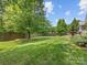 Spacious backyard featuring a well-maintained lawn, wooden fence, mature trees, and a water fountain at 11727 Dunham Dr, Matthews, NC 28105