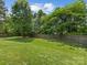 Expansive backyard with well-kept lawn, wooden fence, and mature trees creating a serene outdoor space at 11727 Dunham Dr, Matthews, NC 28105