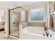 Modern bathroom with glass-enclosed shower, soaking tub, and neutral tile throughout at 11727 Dunham Dr, Matthews, NC 28105
