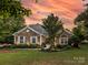 Charming single-story home featuring a stone facade, manicured lawn, and lush landscaping at 11727 Dunham Dr, Matthews, NC 28105
