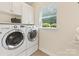 Bright laundry room with storage cabinets, washer and dryer, and a window at 11727 Dunham Dr, Matthews, NC 28105