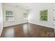 Bright bedroom with dark wood floors and three large windows offering views of the surrounding landscape at 1614 Tarrington Way, Indian Trail, NC 28079