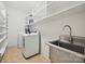 Well-equipped laundry room with washer, dryer, stainless steel sink, and ample shelving for storage at 1614 Tarrington Way, Indian Trail, NC 28079
