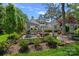 The backyard features lush greenery, mature trees, an outdoor kitchen, and patio at 17924 River Ford Dr, Davidson, NC 28036