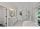 An elegant white bathroom features a dual vanity, glass enclosed shower, and bright window at 17924 River Ford Dr, Davidson, NC 28036