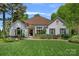 Charming white brick home with well-manicured lawn, mature trees, and inviting entrance, showcasing curb appeal at 17924 River Ford Dr, Davidson, NC 28036