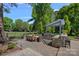 A paved backyard with outdoor kitchen, grill, and a dining area with golf course views at 17924 River Ford Dr, Davidson, NC 28036