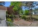 Beautiful outdoor brick patio with stone fireplace, lush landscaping, and mature trees creating a serene backyard retreat at 17924 River Ford Dr, Davidson, NC 28036