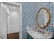 Elegant powder room featuring bold blue wallpaper, gold mirror, and marble countertop sink at 17924 River Ford Dr, Davidson, NC 28036