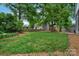 Lush green backyard with a play area nestled amongst mature trees, offering a private retreat at 1816 Lisbon Ln, Charlotte, NC 28269