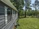 Side view of a gray home with white trim and shutters, surrounded by lush greenery at 1820 Trinity Church Rd, Monroe, NC 28112