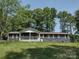 Charming single story home with a cozy covered porch and mature trees surrounding the property at 1820 Trinity Church Rd, Monroe, NC 28112