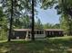 Charming one-story home featuring a covered porch and nestled amongst mature trees at 1820 Trinity Church Rd, Monroe, NC 28112
