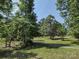 A picturesque lot featuring mature trees, green grass, and a gravel road, offering privacy at 1820 Trinity Church Rd, Monroe, NC 28112