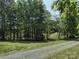 A lot with mature trees, lush greenery and a gravel road, offering a natural and peaceful setting at 1820 Trinity Church Rd, Monroe, NC 28112