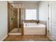 Bathroom features a glass enclosed shower, soaking tub with tile surround, and neutral toned tile flooring at 1876 Yellow Daisy Dr, Matthews, NC 28104