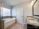 Bright bathroom featuring a soaking tub with tile surround and double vanity with granite countertops at 1876 Yellow Daisy Dr, Matthews, NC 28104