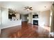 Open-concept living room with a fireplace, hardwood floors, ceiling fan, and adjacent kitchen at 1876 Yellow Daisy Dr, Matthews, NC 28104