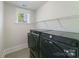 A well-lit laundry room with wire shelving, washer, and dryer at 1909 Summey Ave, Charlotte, NC 28205