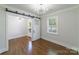 Bright living space featuring hardwood floors, modern sliding barn door, and natural light from a large window at 1909 Summey Ave, Charlotte, NC 28205