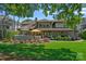 Expansive backyard with stone patio, outdoor kitchen, lush landscaping, and a yellow umbrella at 19501 River Falls Dr, Davidson, NC 28036