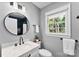 Bathroom with vanity, round mirror, window, and tiled shower in neutral tones at 2008 Highland St, Charlotte, NC 28208