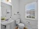 Simple powder room with a pedestal sink, toilet, and a window for natural light at 2025 Groves Edge Ln, Waxhaw, NC 28173