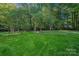 Expansive backyard with a fire pit area and a lush green lawn surrounded by trees at 2500 Little Cove Rd, Charlotte, NC 28270