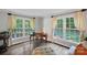 Sunlit living room featuring hardwood floors, large windows, and an elegant writing desk with a colorful ottoman at 2500 Little Cove Rd, Charlotte, NC 28270